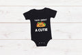 Black baby onesie with white writing that says Taco About A Cutie with a smiling Taco