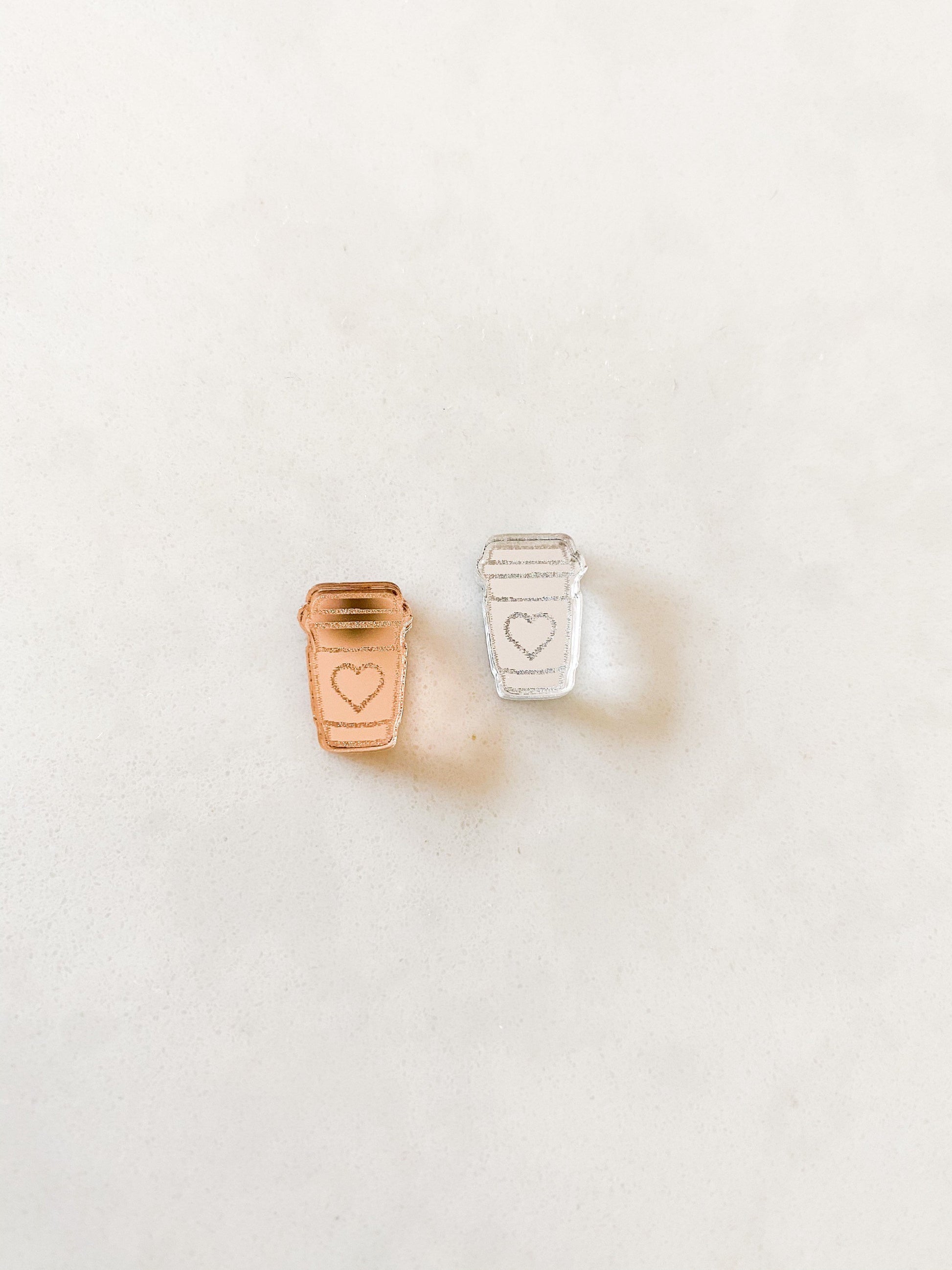 Left rose gold coffee earring with love heart and right is a silver mirror acrylic coffee cup earring with heart.